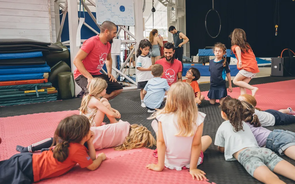 Un grupo de niñas y niños sentados en el tatami escucha a su profesor antes de empezar la clase.