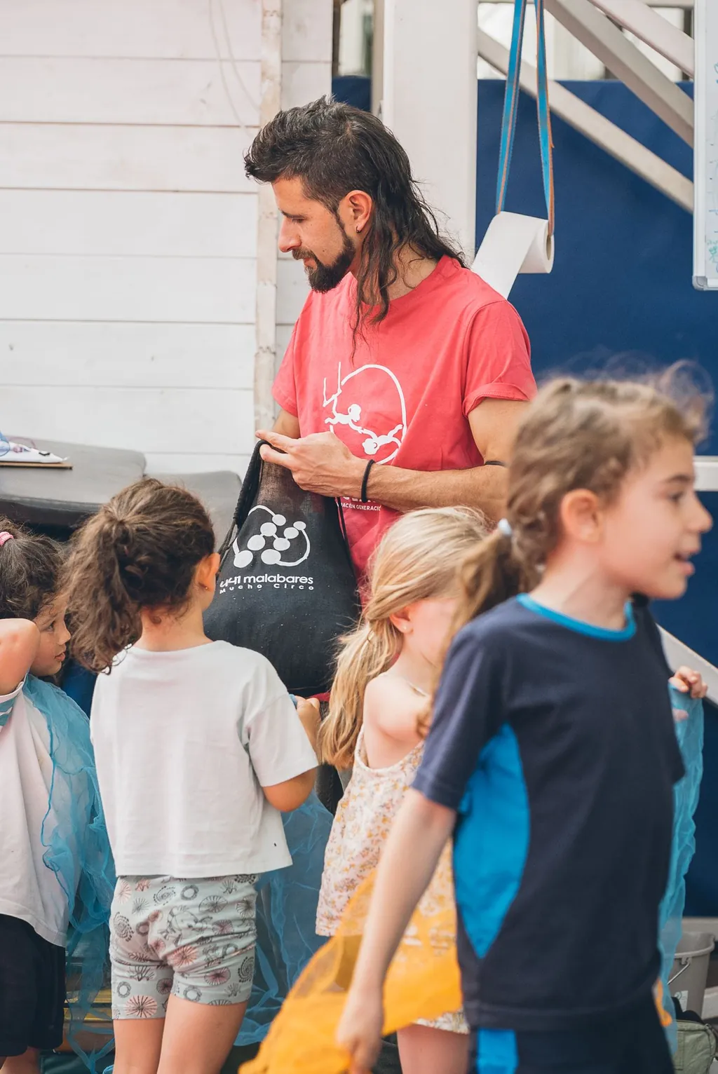Un profesor de la escuela juega con un grupo de niñas y niños durante una actividad.